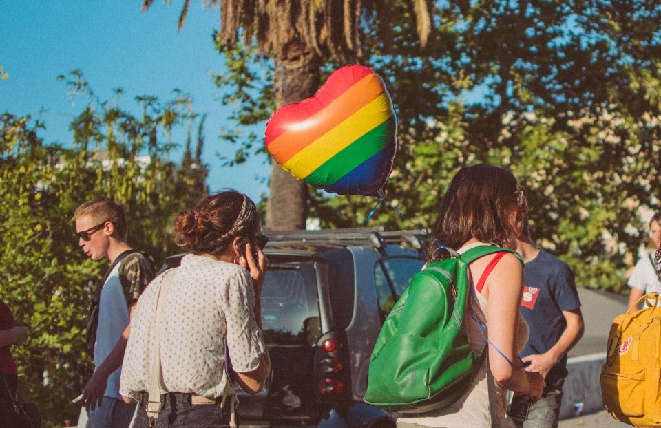 一个人在街上有一个心形的气球与彩虹模式。